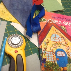 Pinking rotary blade cutter, Laura Wasilowski Fanciful Stitches Colorful quilts book and pieces of fabric with fusible web/appliqué paper ironed on
